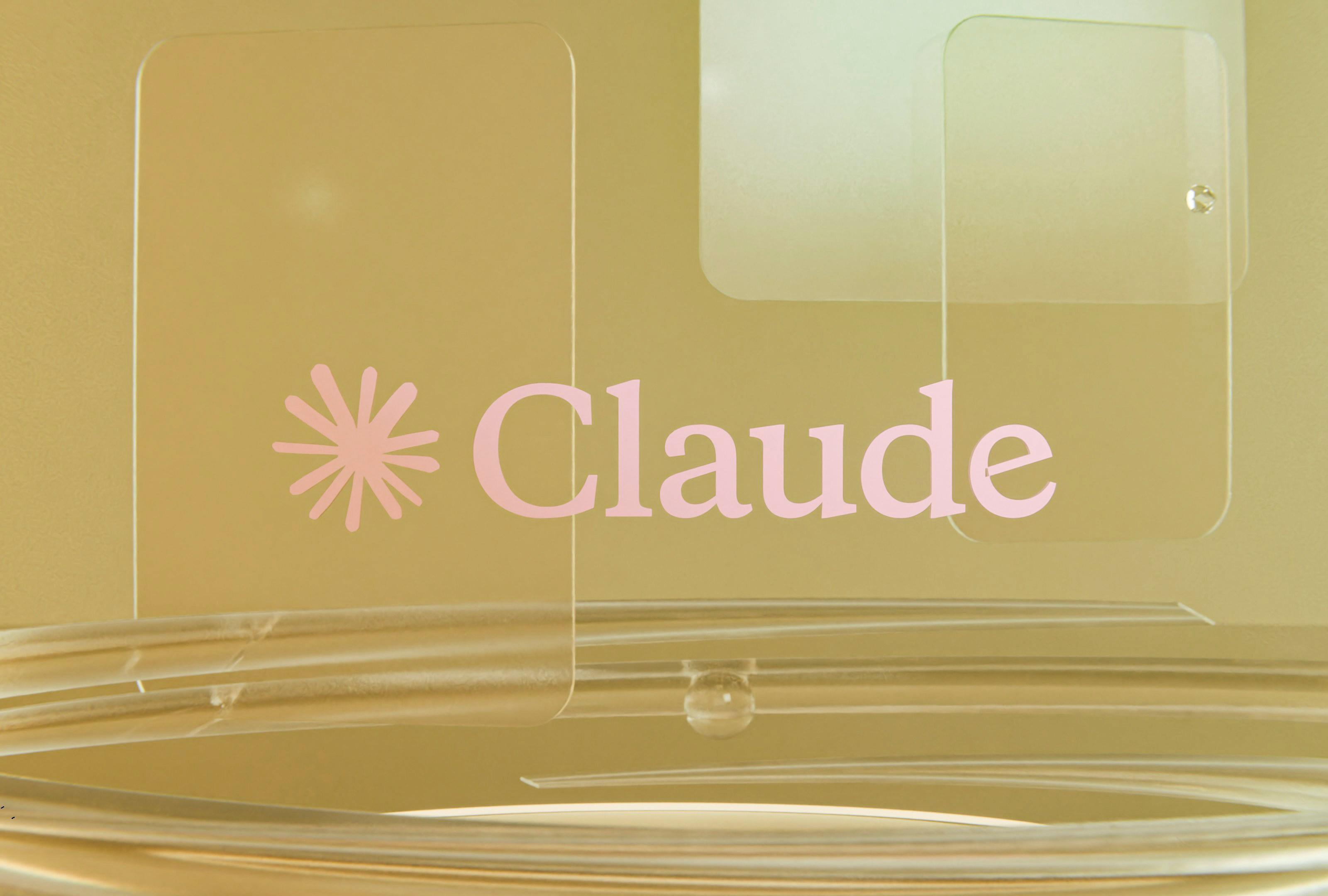 Pink Claude logo rendered on a golden background with glassmorphic elements
