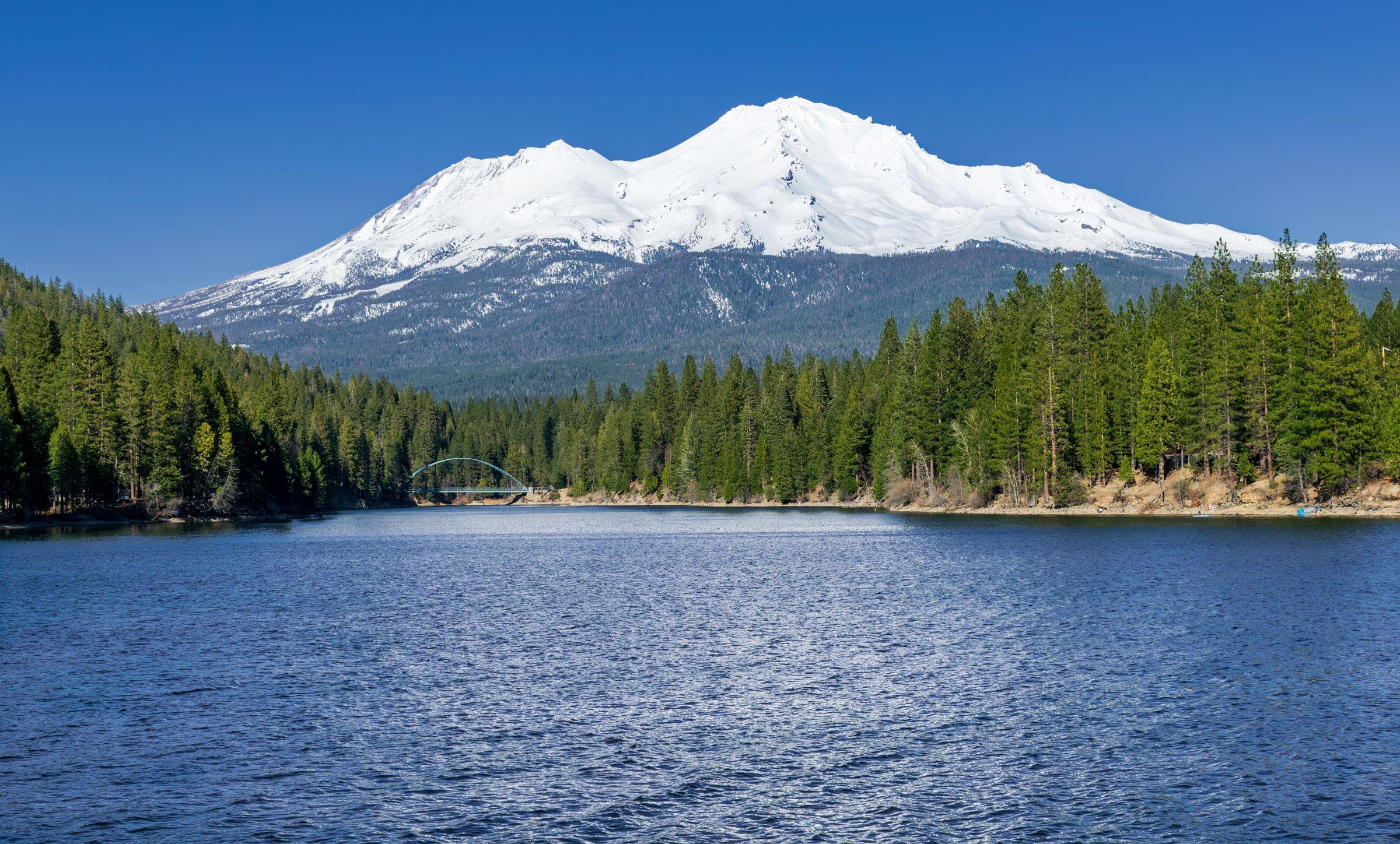 Snow-capped Mount Shasta rising above Lake Siskiyou under a clear blue sky